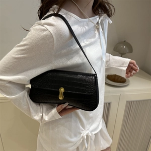 Elegant black crocodile pattern underarm bag with gold lock worn on shoulder