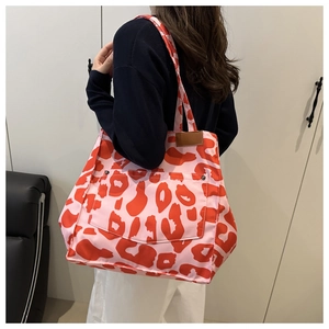Détail d'un grand sac cabas à imprimé léopard avec poche frontale et rivets métalliques