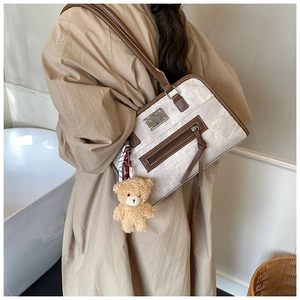 Detail of retro canvas shoulder bag with brown leather trim and teddy bear charm