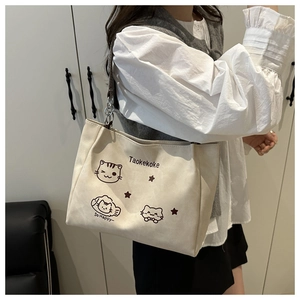 Detail of minimalist cream canvas tote bag with black cartoon cat print and chain strap