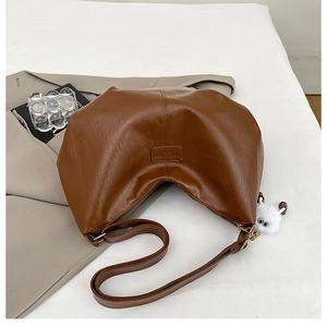 Close-up of brown PU leather hobo bag with vintage texture and plush eye charm detail