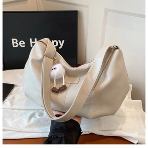 Detail of cream hobo bag with textured leather and cute plush eyeball charm accessory
