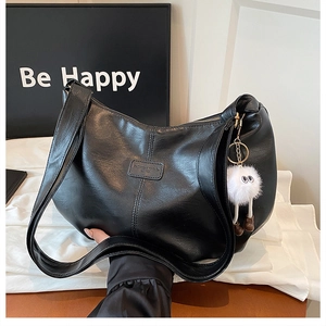 Detail of vintage black tote bag featuring matte leather texture and cute plush charm