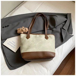 Dettaglio della borsa tote in tela con finiture in pelle marrone e ciondolo a orsetto