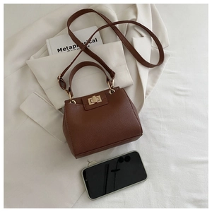 Détail du sac bandoulière en cuir grainé marron avec fermoir rotatif doré et fines bandoulières