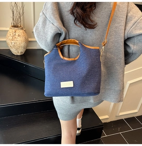 Rear view of a model wearing the denim bucket bag with leather straps on indoor stairs