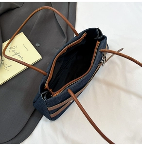 Detail view of the deep blue denim baguette bag interior with a golden zipper pocket