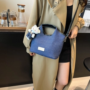 Chic blue denim bucket handbag with leather handles and cute plush bear accessory
