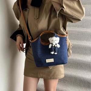 Denim shoulder bucket bag with leather trim and bear pendant in a stylish casual look