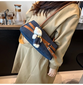 Close-up of denim shoulder bag with brown leather trim and cute plush bear charm