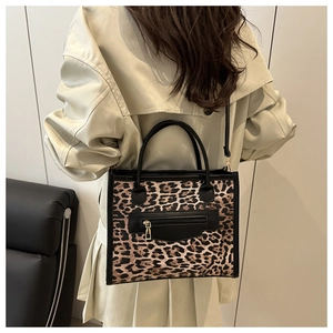Rear view of a model wearing the leopard print handbag with a beige trench coat