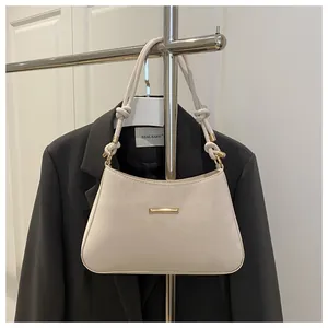 Détail du sac à main en cuir beige avec bandoulière à nœuds et accents métalliques dorés