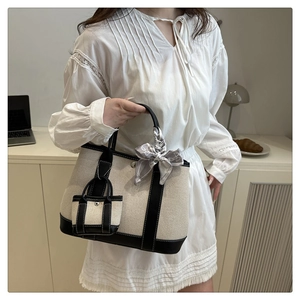 Detail of canvas tote bag with black leather trim and decorative silk scarf on handle