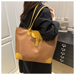 Grand cabas en nylon marron avec anses jaunes porté à l'épaule par un mannequin