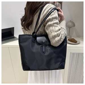 Détail du grand sac cabas noir en nylon et cuir porté par un mannequin en ambiance chaude