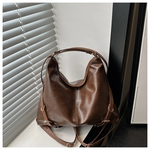 Detail of vintage brown leather hobo bag with gold hardware on a sunlit windowsill