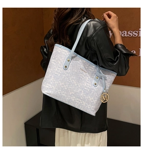 Detailed view of tote bag with blue plaid pattern and elegant gold M charm pendant