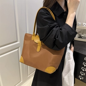 Grand sac cabas en nylon marron avec finitions en cuir jaune porté par un mannequin