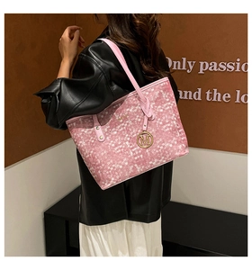 Detailed view of pink textured tote bag featuring gold metallic M charm and shoulder strap
