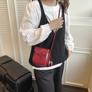 Elegante borsa a tracolla in vernice rossa con pendenti a fragola indossata da modella
