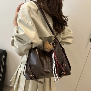 Vintage dark brown tote bag with metal buckles and plush bear pendant shown on model