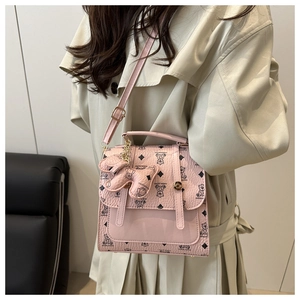 Detailed side view of a pink polka dot backpack featuring cartoon bear patterns and a cute charm