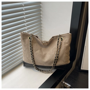 Detalle del bolso tote de ante marrón con acolchado de rombos y cadena dorada