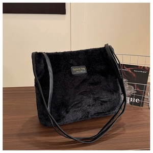 Détail du sac seau noir en peluche avec écusson en cuir et texture de fausse fourrure