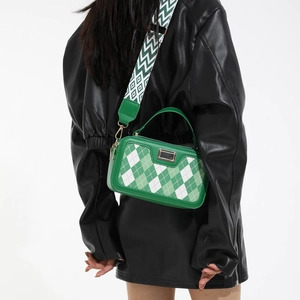 Groen-witte geblokte crossbodytas met brede golvende schouderband op het model