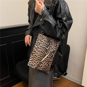 Fashionable leopard print envelope crossbody bag with gold metal trim and leather jacket styling