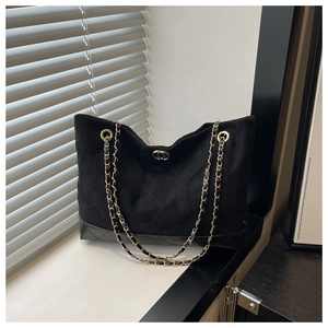 Detalle del bolso tote de ante negro con base de cuero acolchado y cadena dorada