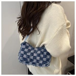 Detail of frayed edge denim plaid handbag shown on model with cozy knit sweater
