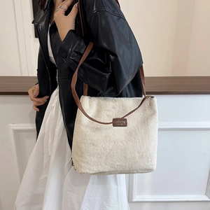 Sac à bandoulière en peluche blanche avec sangle en cuir marron et étiquette mode