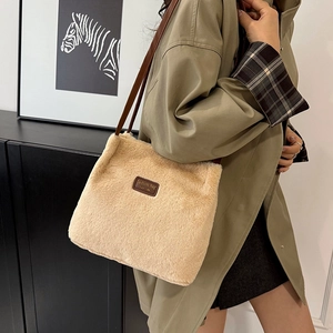 Sac seau en fausse fourrure beige avec bandoulière marron et étiquette en cuir