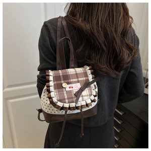 Close-up of brown checkered flap with coffee ruffle trim and cherry badge on small backpack
