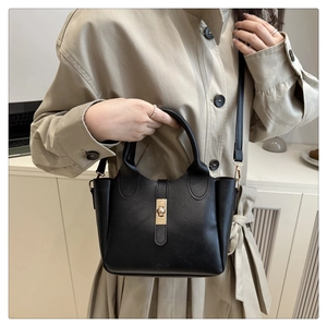 Détail d'un sac seau noir en cuir avec fermoir doré tournant et inscription FASHION