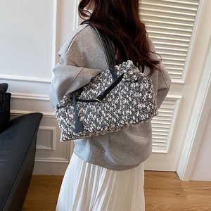 Classic black and white tweed tote bag with leather handles shown on a model