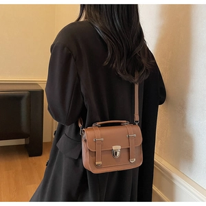 Sac bandoulière en cuir marron porté par un mannequin avec bandoulière et boucle en métal