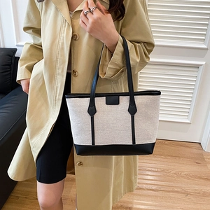 Minimalist canvas tote bag with black leather trim and handles shown on a model
