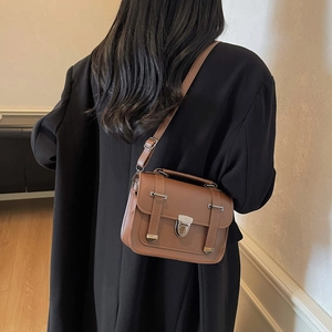 Sac bandoulière vintage marron avec poignée et boucles argentées sur mannequin