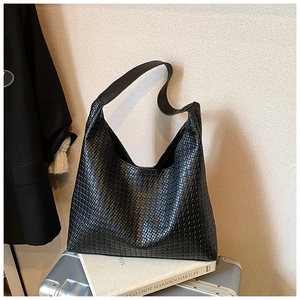 Dettaglio della trama intrecciata nera e tracolla larga sulla borsa tote grande