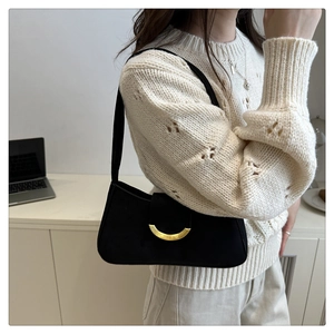 Détail du sac sous l'aisselle en daim noir avec boucle en métal doré sur modèle