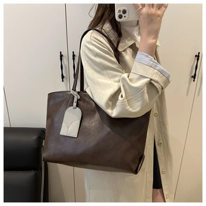 Detail of vintage brown leather tote bag showing textured soft skin and shoulder strap