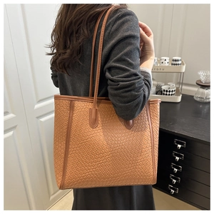 Detail of a brown woven tote bag showing the textured faux leather and long shoulder strap
