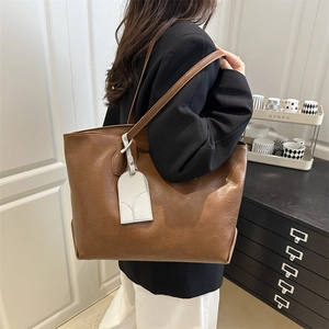 Brown faux leather tote bag with large capacity and white charm shown on female model