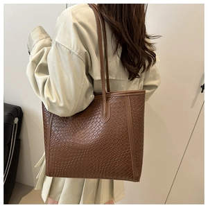 Brown woven tote bag detail showing dense diamond weave texture on synthetic leather surface