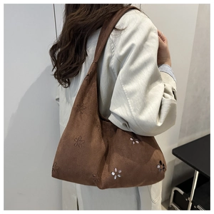 Dettaglio della borsa tote in pelle scamosciata marrone con trafori floreali e paillettes