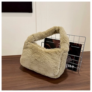 Détail d'un sac à épaule en peluche kaki avec fermeture éclair dorée sur bois