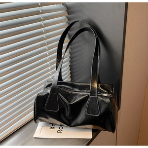Detailed close-up of glossy black shoulder bag texture with natural crinkle leather effect