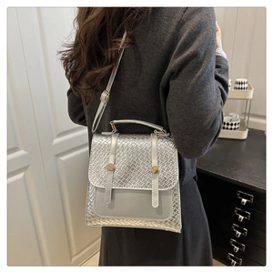 Détail d'un sac à dos argenté tressé avec boucles dorées dans un décor intérieur chic